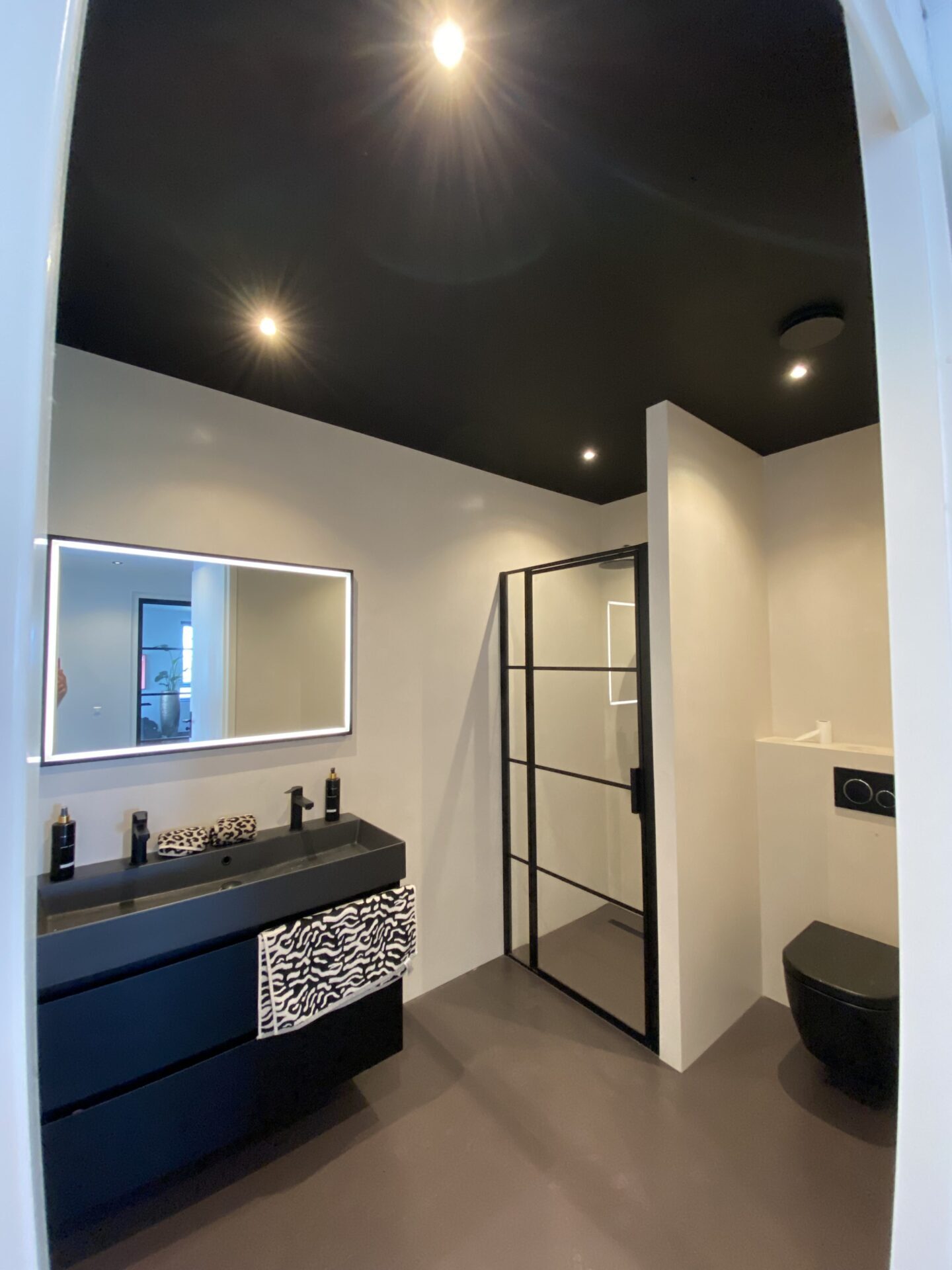 Impressie van badkamer met spanplafond met verlichting